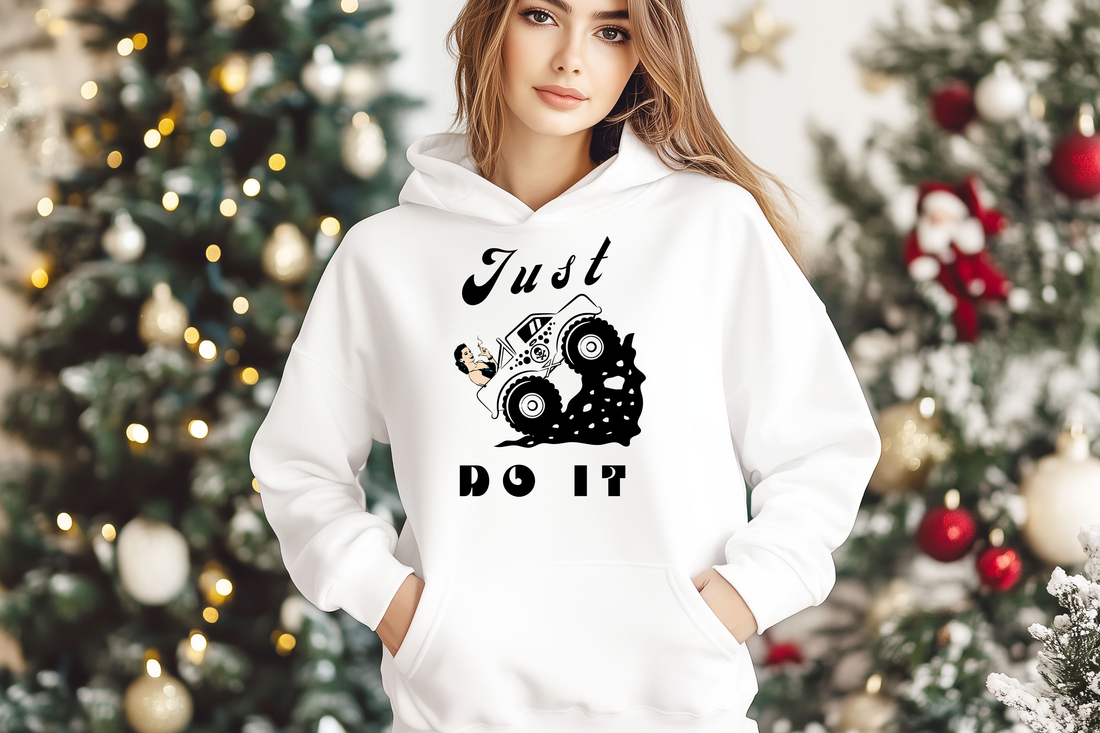 Woman wearing a white hoodie with 'Just Do It' slogan and a cartoon monster truck design, perfect for casual wear and gift ideas for truck enthusiasts during the holiday season.