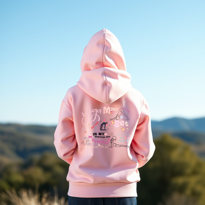 Back view of a pink hoodie featuring colorful yoga-inspired graphics and affirmations, promoting mindfulness, meditation, and self-care, set against a scenic outdoor background with hills and a clear sky.